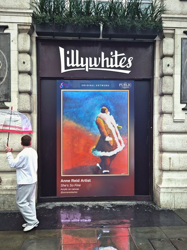 She’s So Fine by Anne Reid on the Lillywhites screen at Piccadilly Circus, with a passer-by holding an umbrella